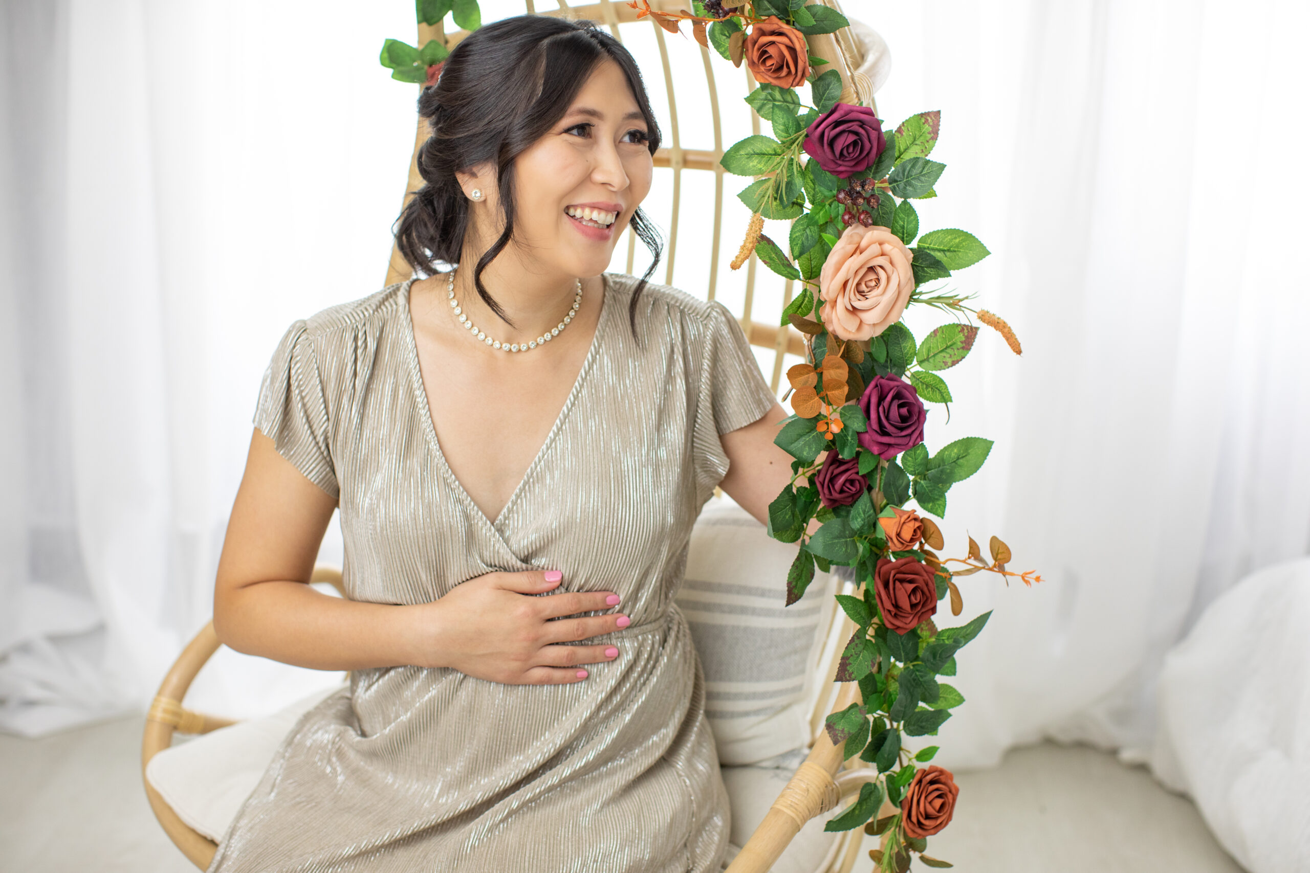 Joyful expectant mom in gold dress from Baltic Born and flower decor.