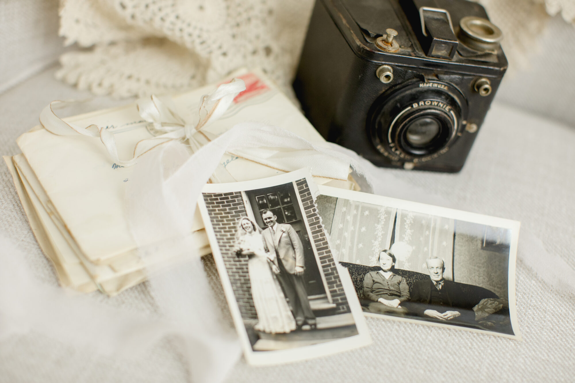 Old family photos and letters with a vintage brownie camera depicts the precious nature of printed photos.